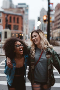 Cheerful friends crossing road in city