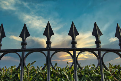 Low angle view of metal fence against sky