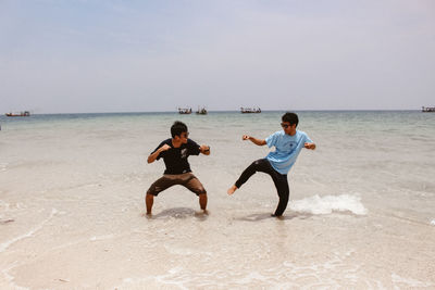 Full length of boys on beach against sky