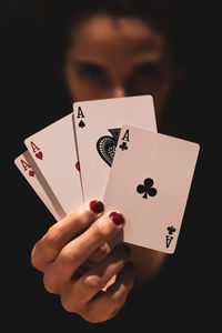Close-up of woman holding cards against black background