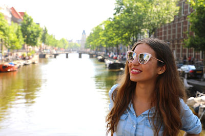 Young woman standing by canal in city