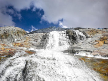 Scenic view of waterfall against sky