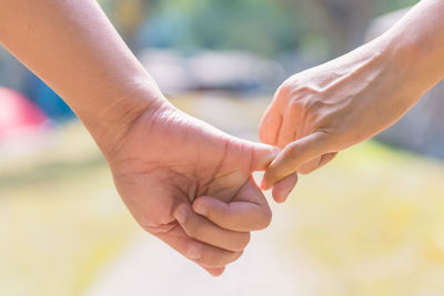 Close-up of friends taking pinky promise outdoors