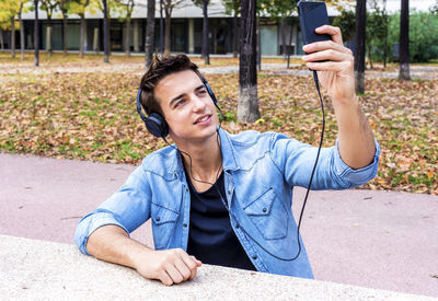 Man listening music while taking selfie in city