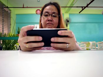 Serious mature woman using phone on restaurant table