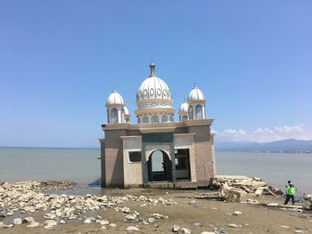 Church by sea against clear blue sky