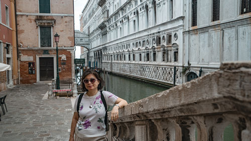 Portrait of young woman standing against building