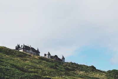 Low angle view of houses on grassy hill against sky