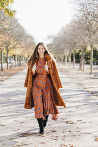 Portrait of young woman standing against trees