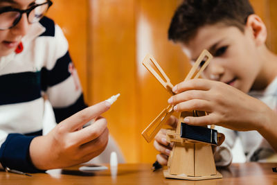 Close-up of male friends making toy windmill on table at home