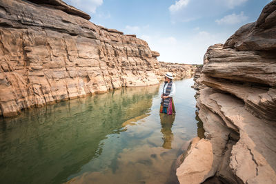 Reflection of woman on rock formation against sky