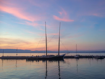 Sailboats in sea against sky during sunset