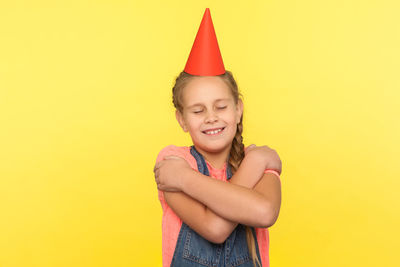 Portrait of smiling girl standing against yellow background