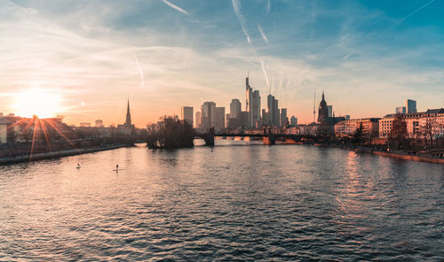 River in city against sky during sunset