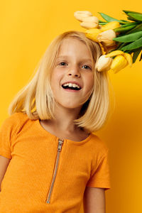 Portrait of young woman against yellow background