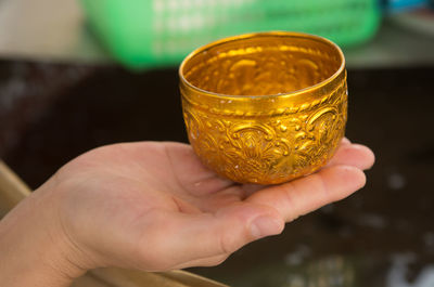 Close-up of person holding gold bowl