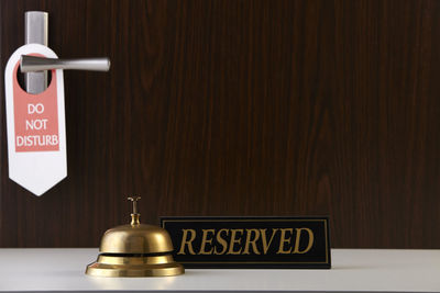 Close-up of information sign on table against wall