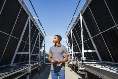 Employee with digital tablet checking refrigeration installation on rooftop