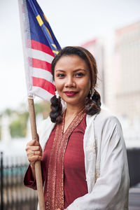 Portrait of young woman holding american flag