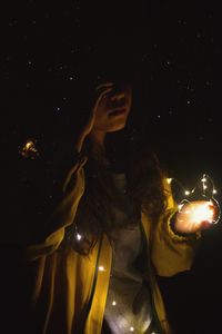 Digital composite image of woman with arms outstretched at night