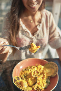 Beautiful young girl tasting a delicious rice with seafood, peruvian food called arroz con mariscos