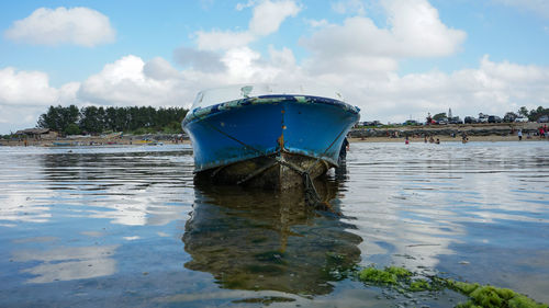 Boat moored on lake against sky