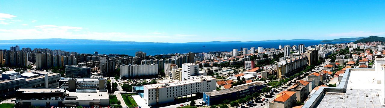 city, building exterior, cityscape, architecture, built structure, blue, high angle view, crowded, sky, residential district, city life, skyscraper, residential structure, clear sky, sea, residential building, day, water, outdoors, office building