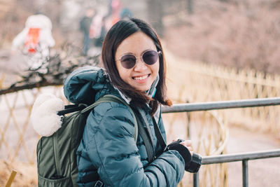 Portrait of smiling young woman holding camera
