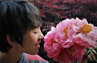 Close-up of smiling boy smelling pink flowers