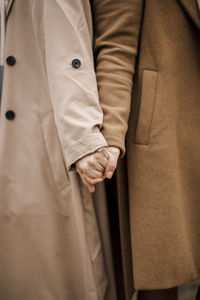 Women wearing overcoats holding hands