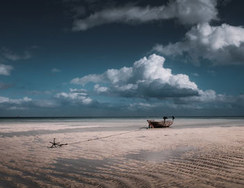 Boat moored at beach against sky