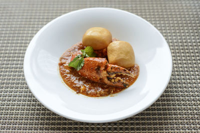 Close-up of chilli crab with fried mantou in plate on table