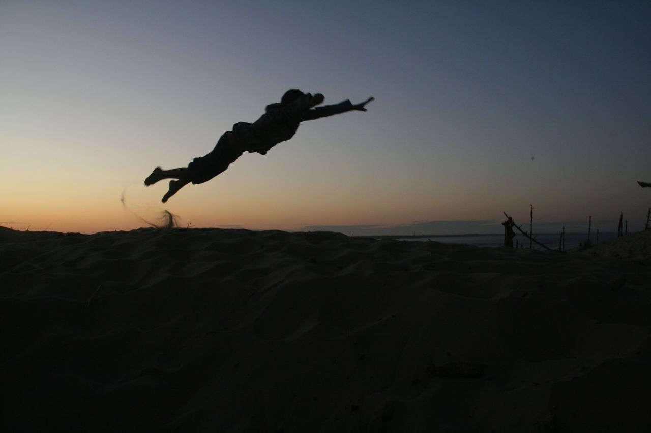 SILHOUETTE MAN JUMPING ON BEACH AGAINST SKY DURING SUNSET