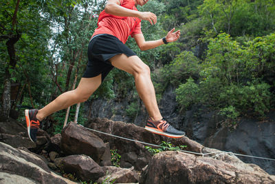 Full length of man jumping on rock in forest