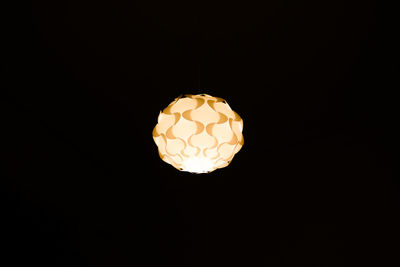 Low angle view of illuminated light bulb against black background