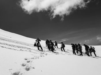 People on snow covered land against sky