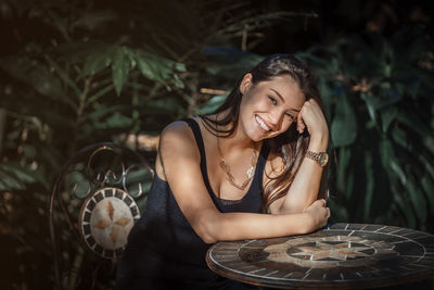 Beautiful young latina woman sitting at a table with jungle type background
