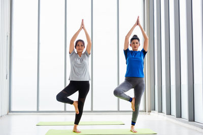 Full length portrait of smiling women exercising at yoga studio