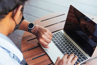 Midsection of man wearing mask using laptop at cafe