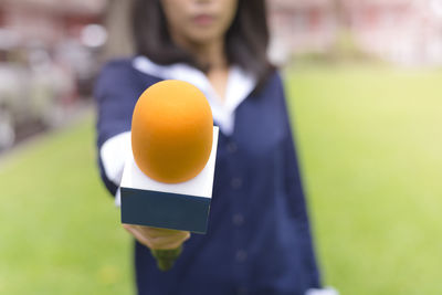 Midsection of woman holding yellow while standing outdoors