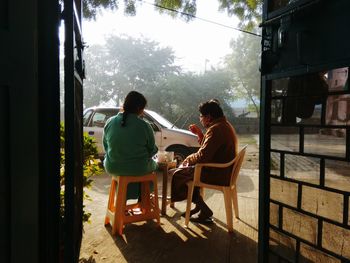 Rear view of an old man and woman sitting on bench