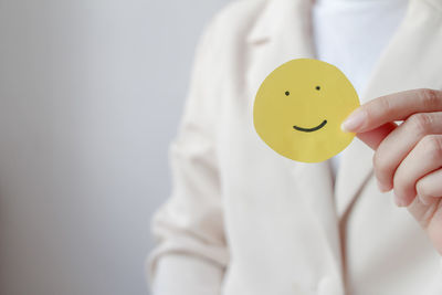 Midsection of doctor holding dentures against white background