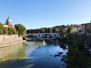 Arch bridge over river against clear sky