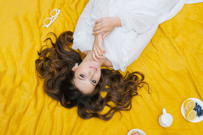 Top view of a beautiful romantic woman in a dress, lying on the green grass on a yellow blanket. 