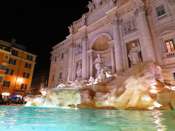 Fountain in front of buildings at night