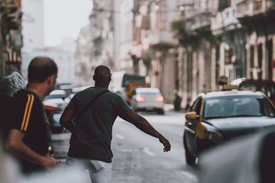 Rear view of people walking on street in city