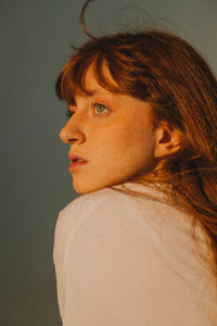 Close-up of young woman looking away against wall