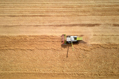 Aerial view of working harvesting combine in wheat field, harvest season