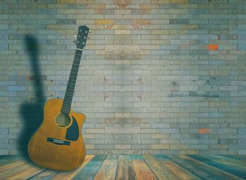 Close-up of guitar against brick wall