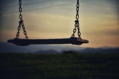 Silhouette of swing against sky during sunset